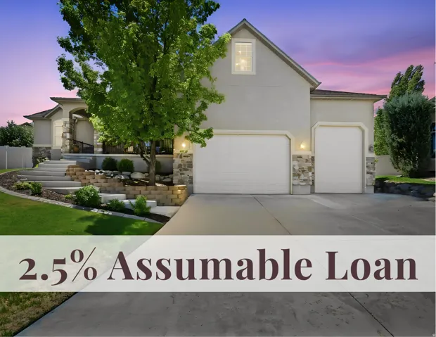 Stucco and stone exterior, two-car garage, terraced landscaping with retaining walls, and a covered entry