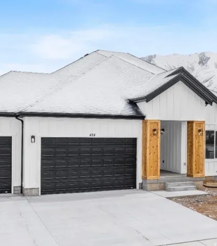 Contemporary exterior featuring a black and white color palette, a two-car garage, wood-clad architectural columns, and a covered entry