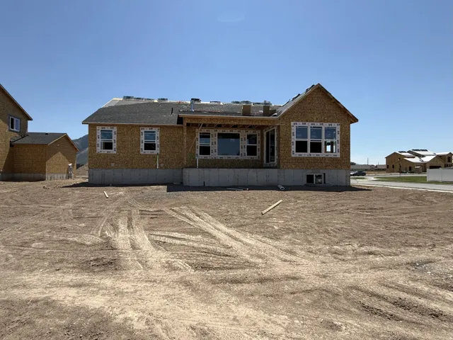 Single-story residential structure under construction, featuring a plywood exterior and a dark shingle roof