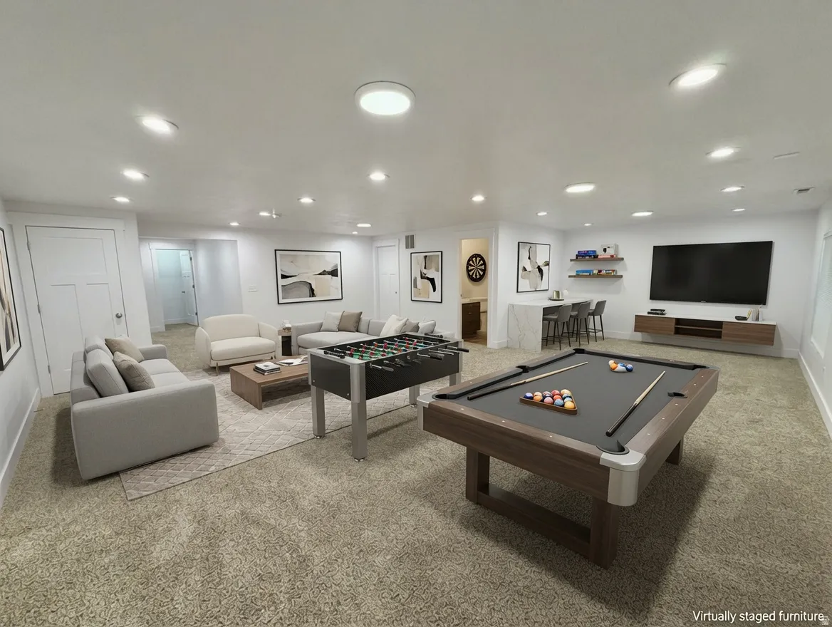 Spacious entertainment room featuring recessed lighting, a built-in bar with seating, floating wall shelving, and a wall-mounted media console
