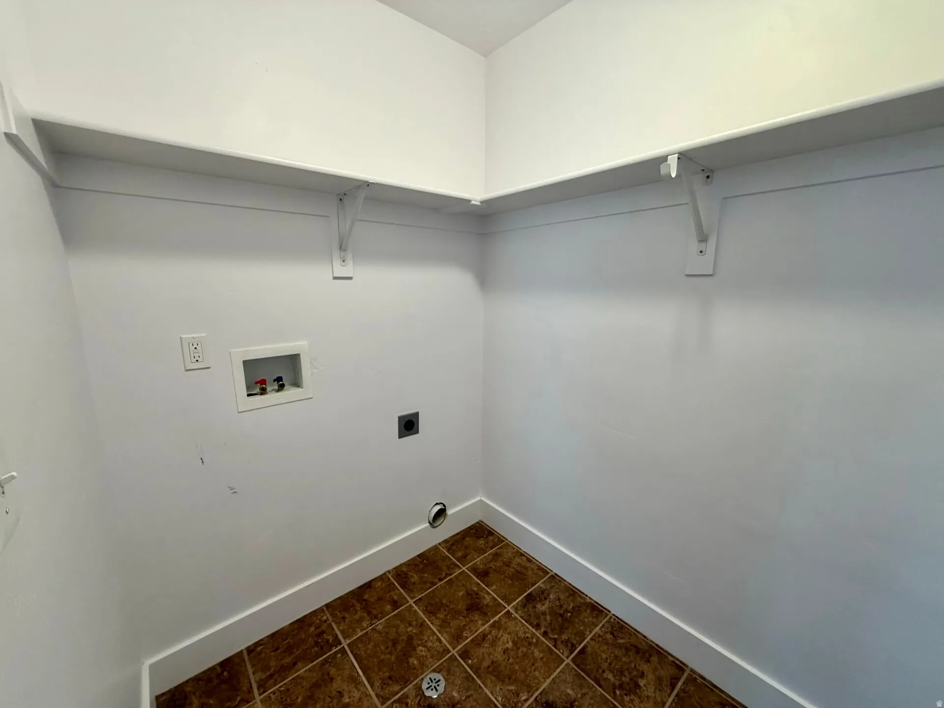 Utility room featuring tile flooring, white walls, and built-in shelving