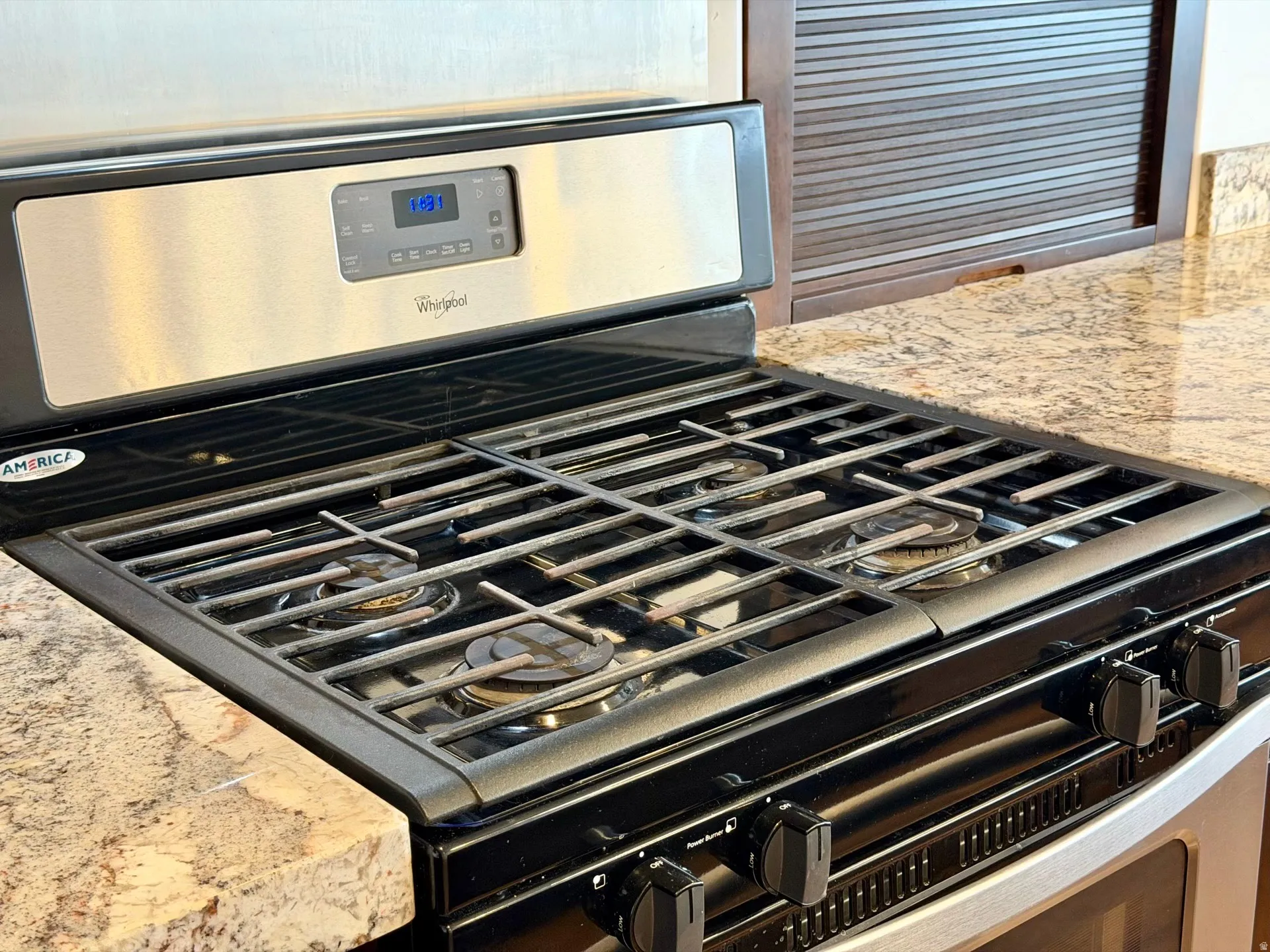 Stainless steel range with a black cooktop and grates