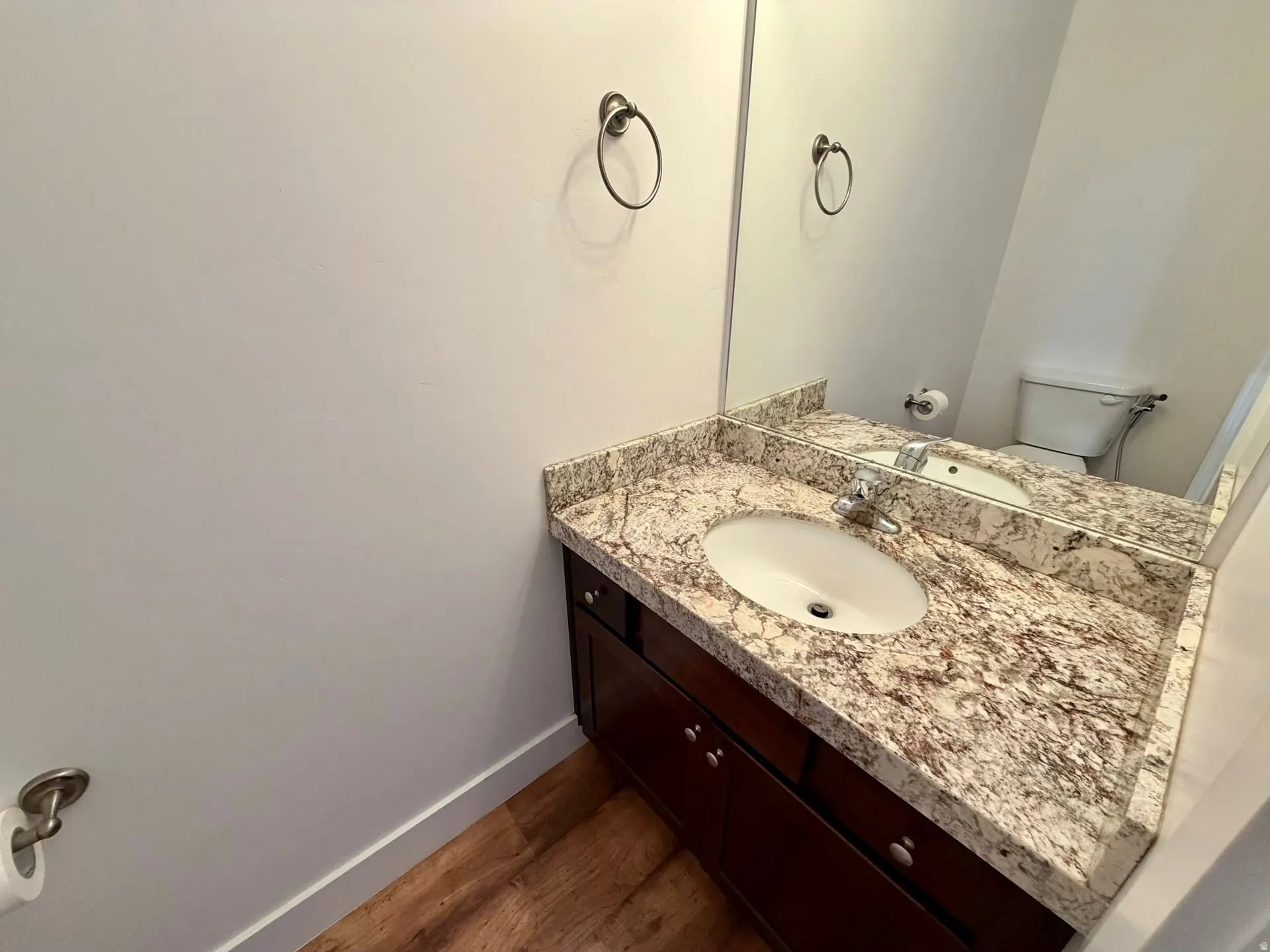 Bathroom vanity with an integrated oval sink and granite countertop, featuring a large wall-mounted mirror