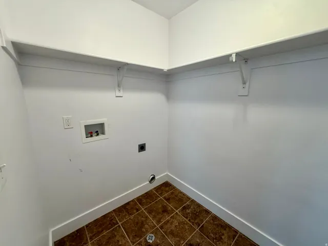 Utility room featuring tile flooring, white walls, and built-in shelving