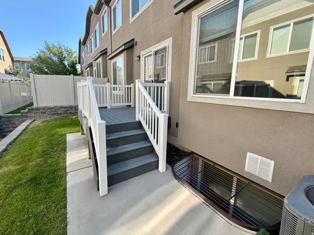 Private rear patio deck with stairs to a concrete landing