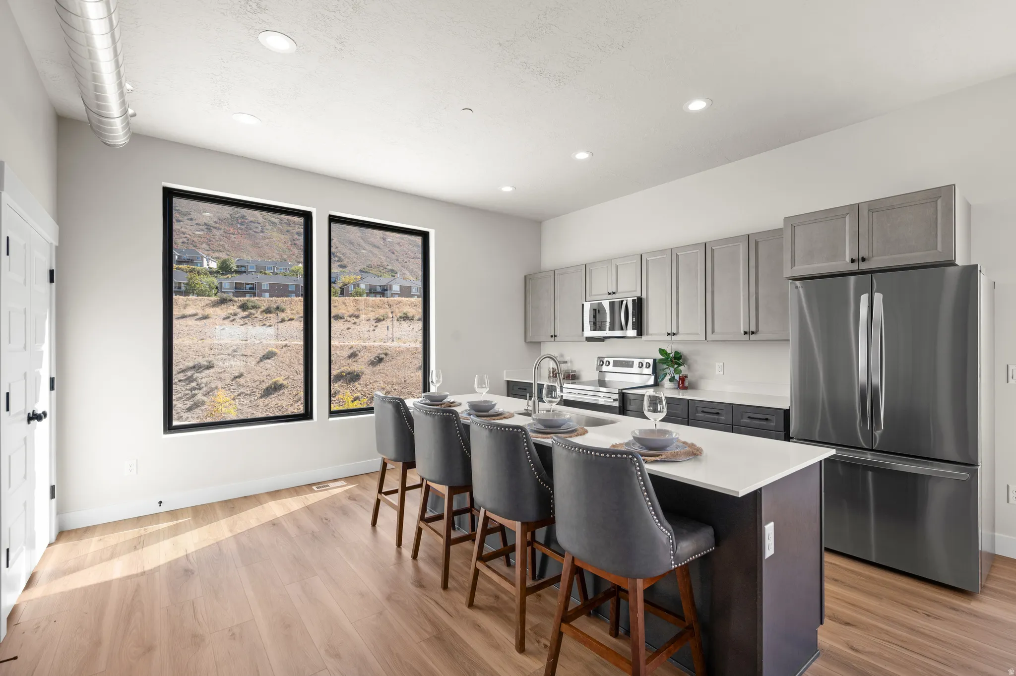 Modern kitchen featuring an island with seating, stainless steel appliances, wood-finish flooring, and recessed lighting