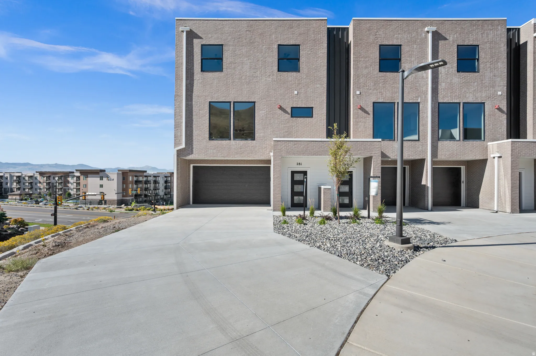 Modern townhome featuring a textured facade, black-framed windows, and an integrated garage