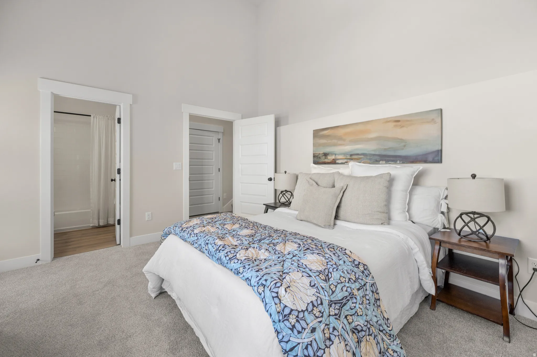 Carpeted bedroom featuring a vaulted ceiling and light neutral wall tones