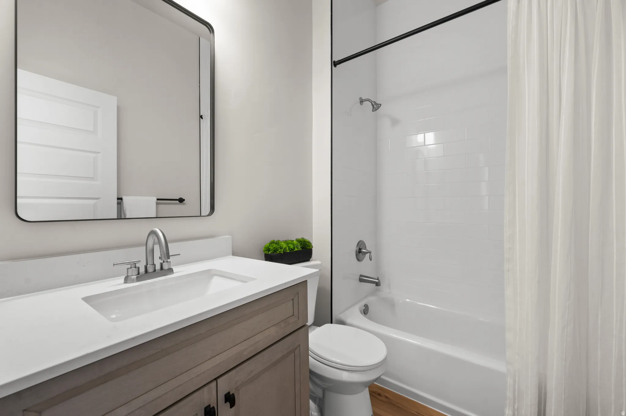 Modern bathroom featuring a single vanity with wood-finish cabinetry, a white countertop, and an integrated rectangular sink with a brushed nickel faucet