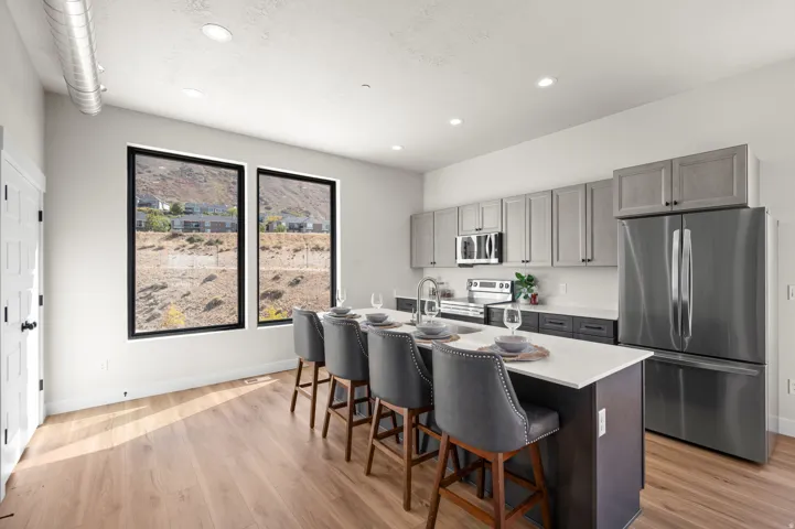 Modern kitchen featuring an island with seating, stainless steel appliances, wood-finish flooring, and recessed lighting