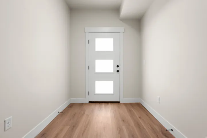 Entryway featuring a white door with three glass panels, wood-finish flooring, and crisp white trim