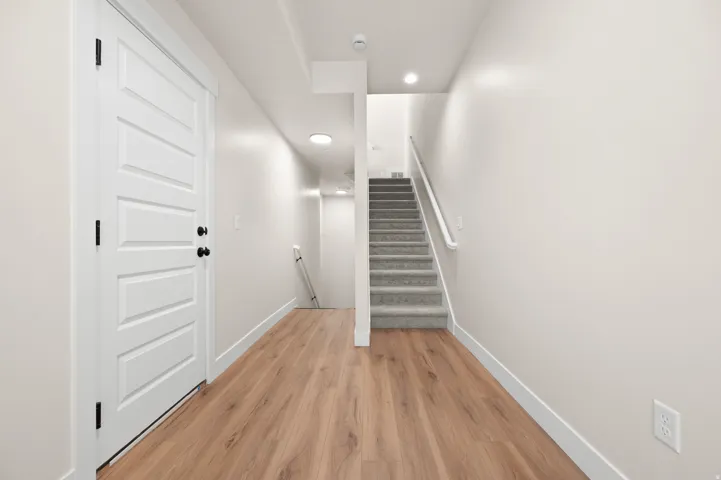 Entryway featuring light wood-finish flooring, a contemporary five-panel door with matte black hardware, and crisp white baseboards