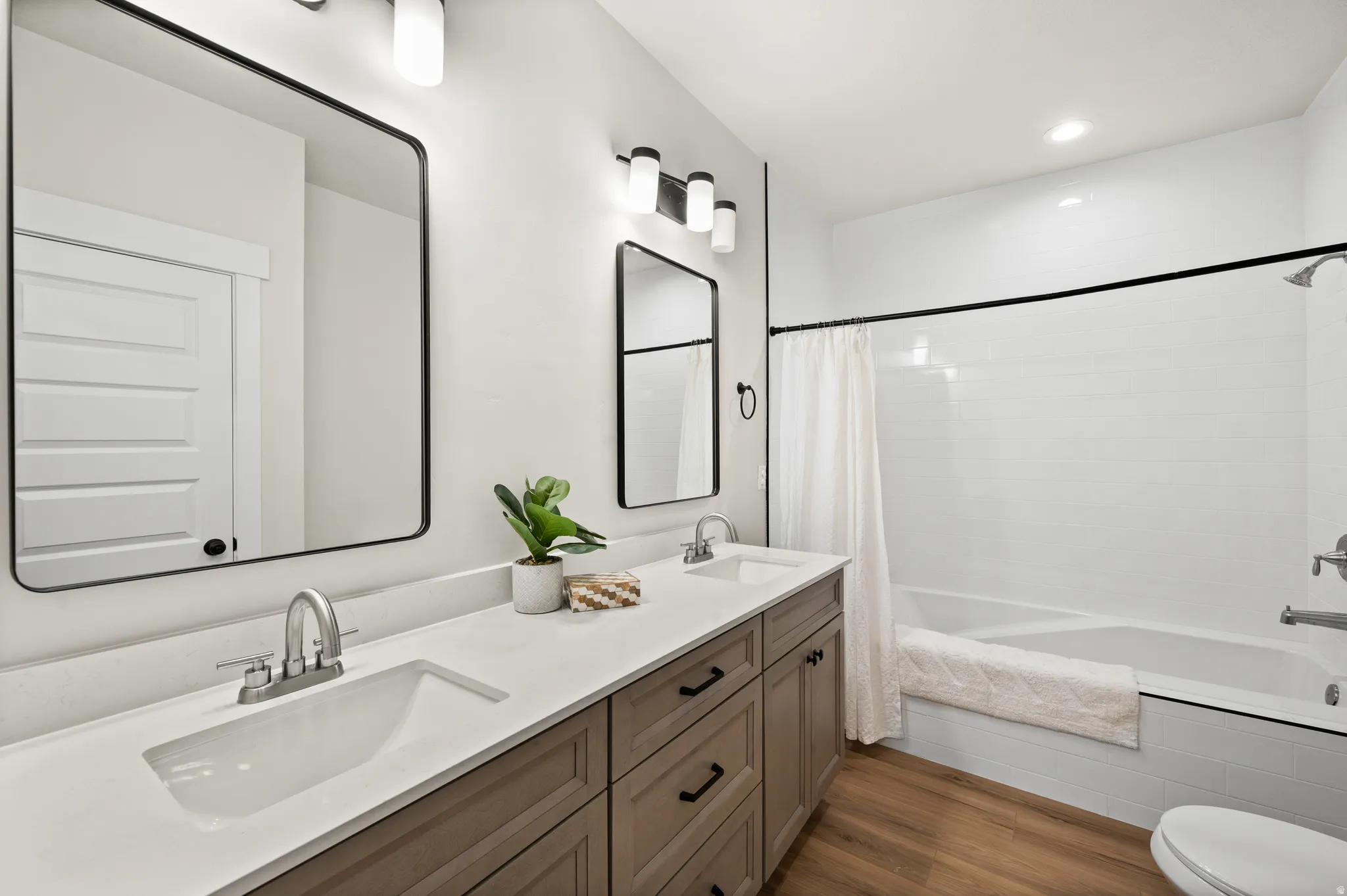 Full bathroom featuring a double vanity with integrated sinks, brushed nickel fixtures, and a light wood-finish cabinet base