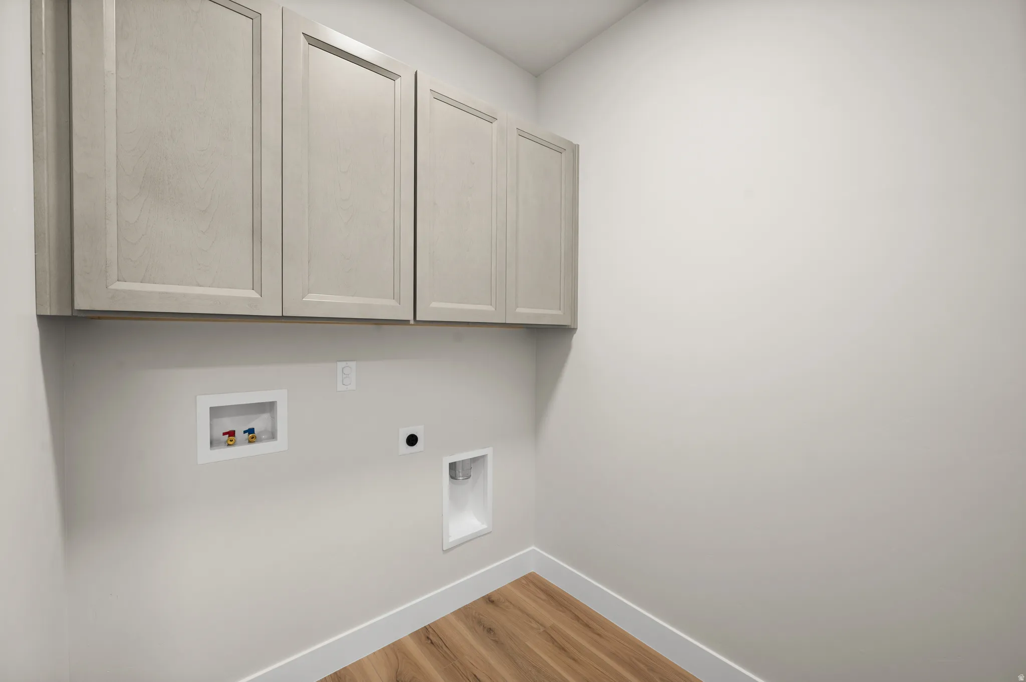 Laundry area featuring wood-finish flooring, white baseboards, and light-toned wall paint