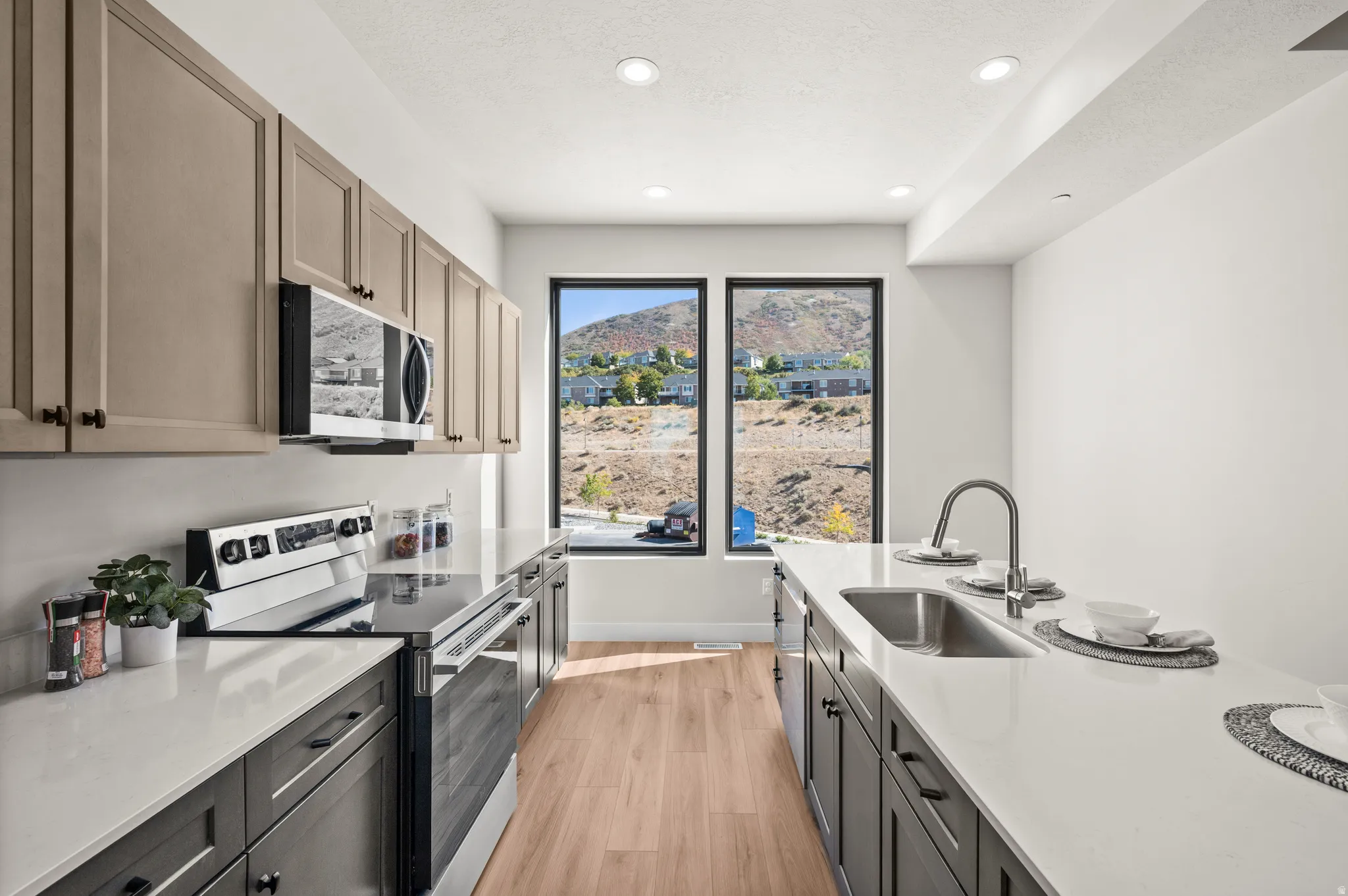 Modern kitchen featuring contrasting cabinetry, stainless steel appliances, and light wood-finish flooring