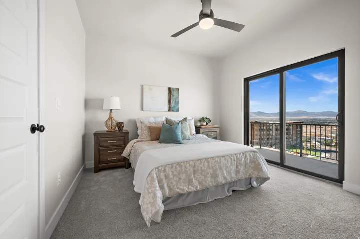 Bedroom featuring a ceiling fan with integrated lighting, light gray carpet flooring, and a sliding glass door leading to a private balcony