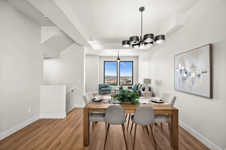 Open-concept dining and living area featuring wood-finish flooring, a contemporary multi-light chandelier, and coffered ceiling details