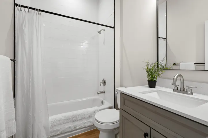 Full bathroom featuring a white subway tile shower surround, a white bathtub, and a wood-finish floor