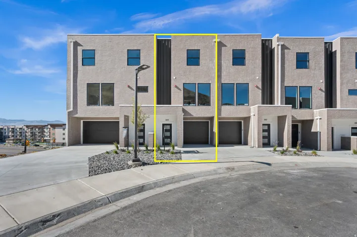 Contemporary townhome featuring a neutral stucco exterior with dark vertical accent panels