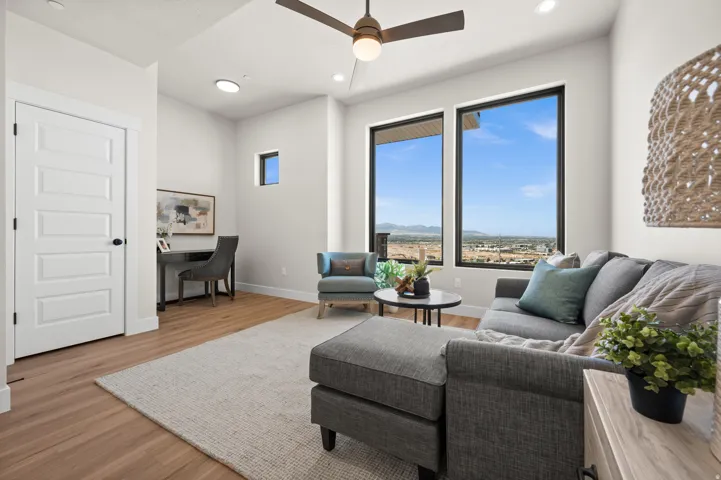 Spacious room featuring wood-finish flooring, white trim, and a ceiling fan