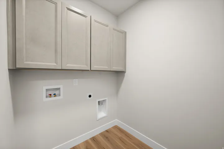 Laundry area featuring wood-finish flooring, white baseboards, and light-toned wall paint