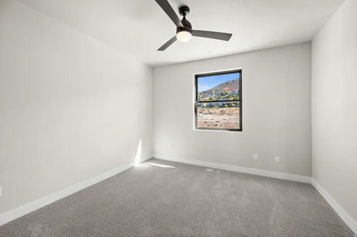 Room featuring neutral-toned walls, grey carpeting, and a window with a black frame
