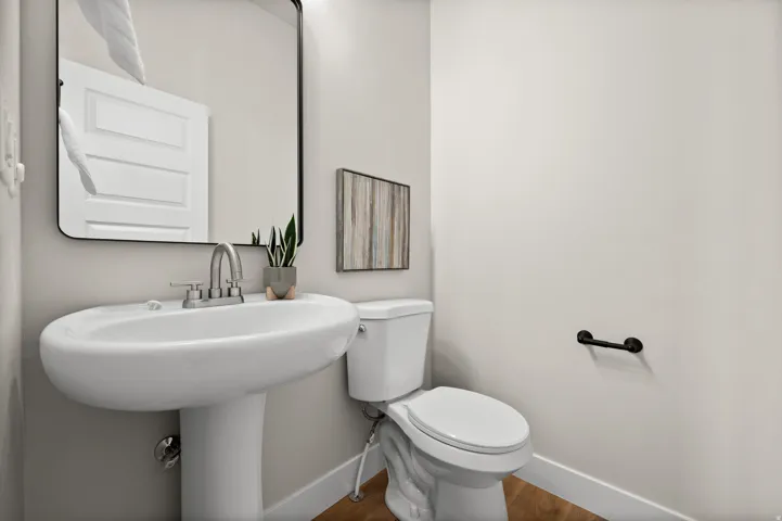 Pedestal sink with chrome faucet, complemented by a rectangular mirror with a black frame