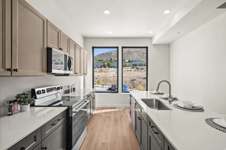 Modern kitchen featuring contrasting cabinetry, stainless steel appliances, and light wood-finish flooring