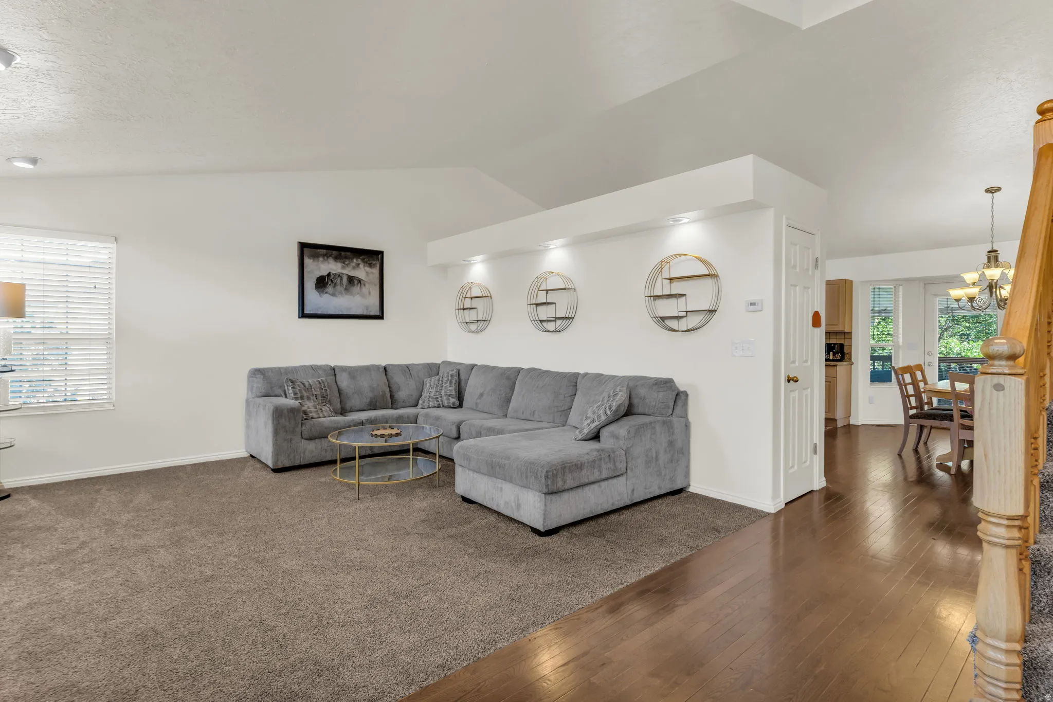 Expansive living area featuring vaulted ceilings, recessed lighting, and a blend of plush carpeting and wood-finish flooring