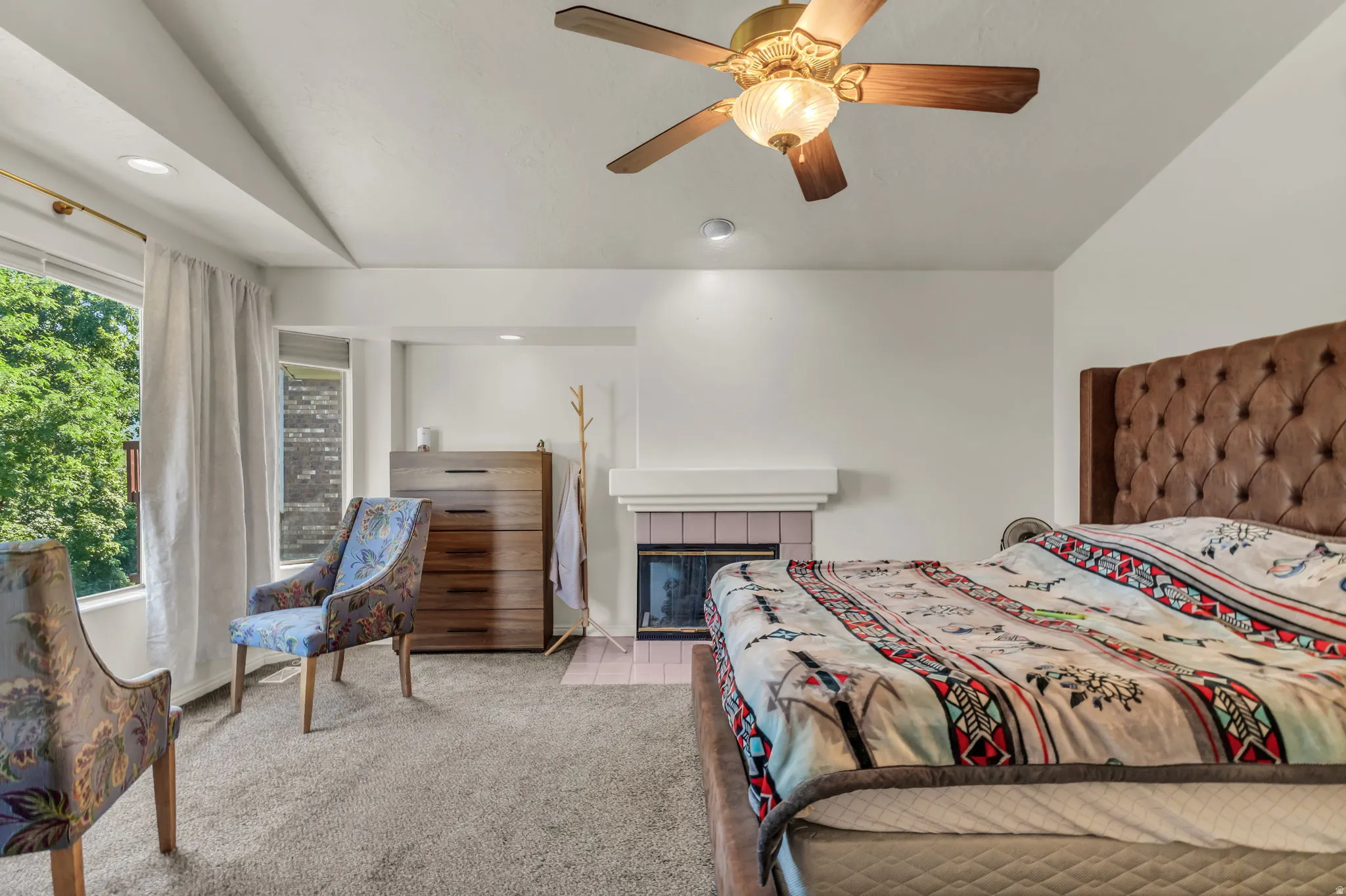 Spacious primary bedroom featuring a tufted upholstered headboard, ceiling fan with integrated lighting, recessed ceiling lights, and direct access to a private outdoor space