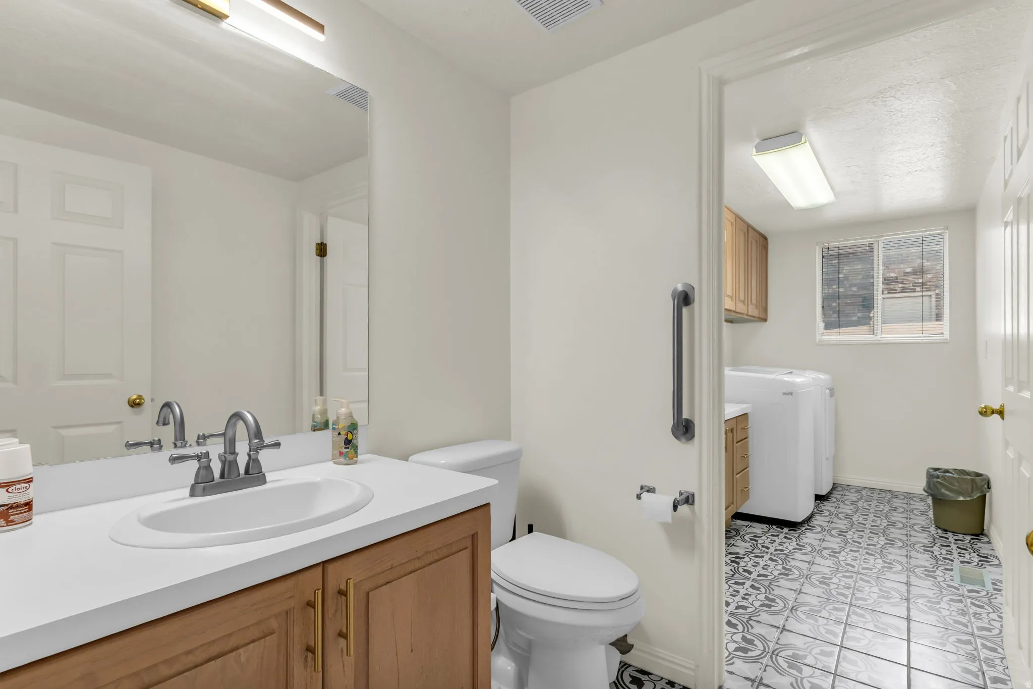 Bathroom vanity featuring a single basin, light-toned wood cabinetry, and a white countertop