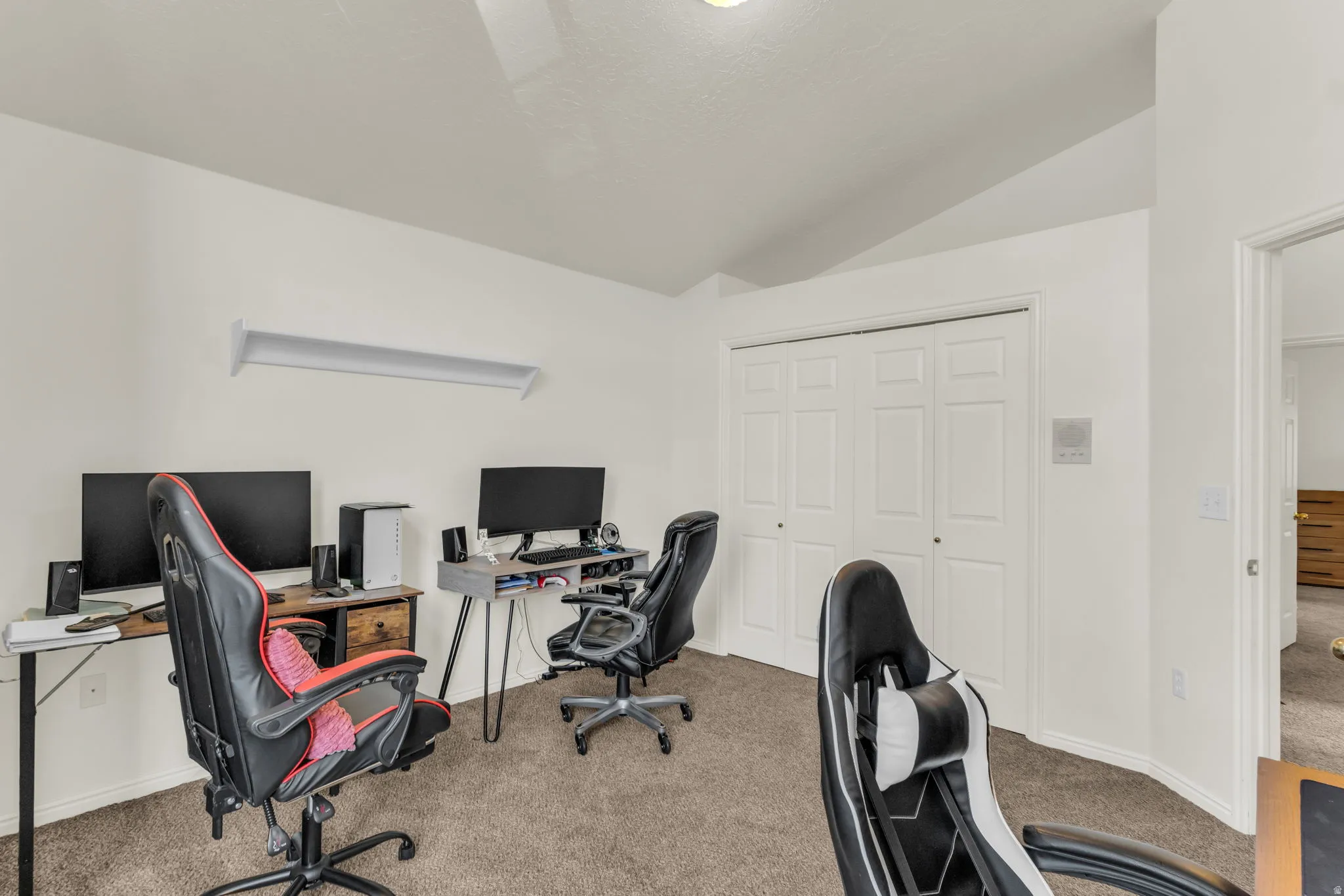 Room featuring neutral carpet flooring, white painted walls, and a vaulted ceiling
