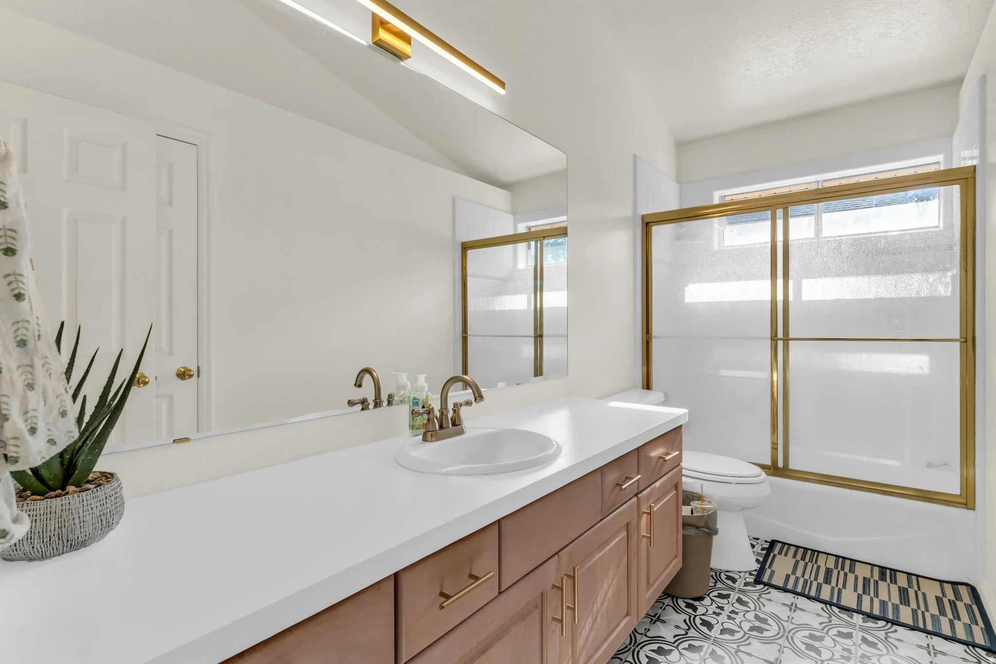 Bathroom featuring an extended vanity with a white countertop, single sink, and brass-tone hardware