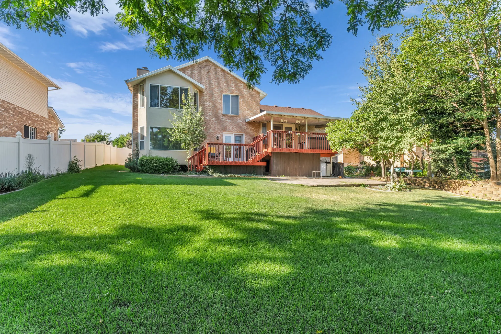 Expansive green lawn with a two-story residence featuring a brick facade and light-colored siding