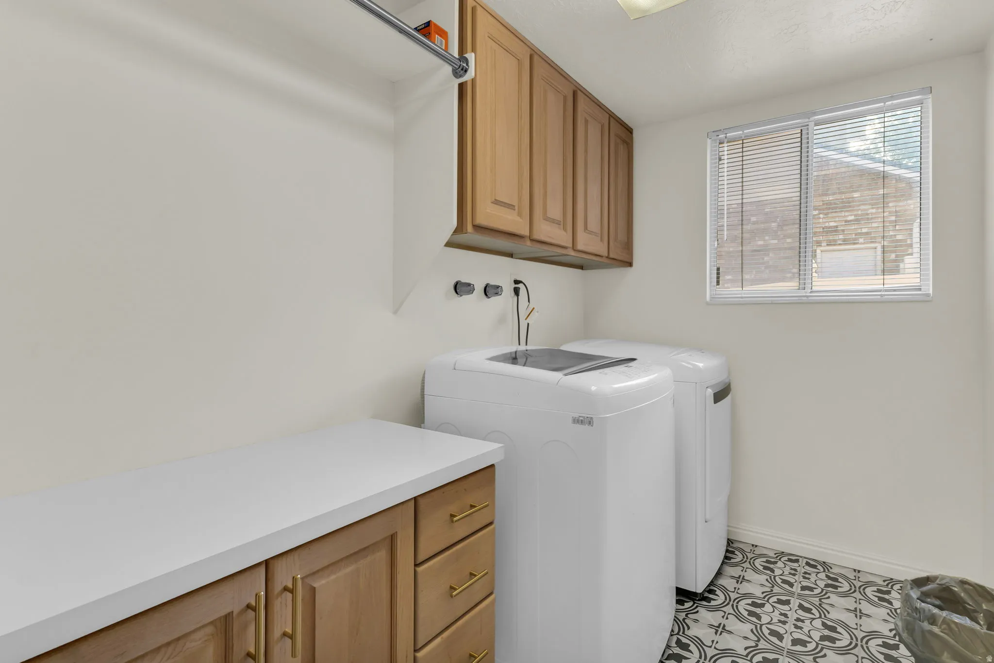 Utility room featuring a built-in folding counter with wood-finish cabinetry, an overhead hanging rod, and patterned floor tiles