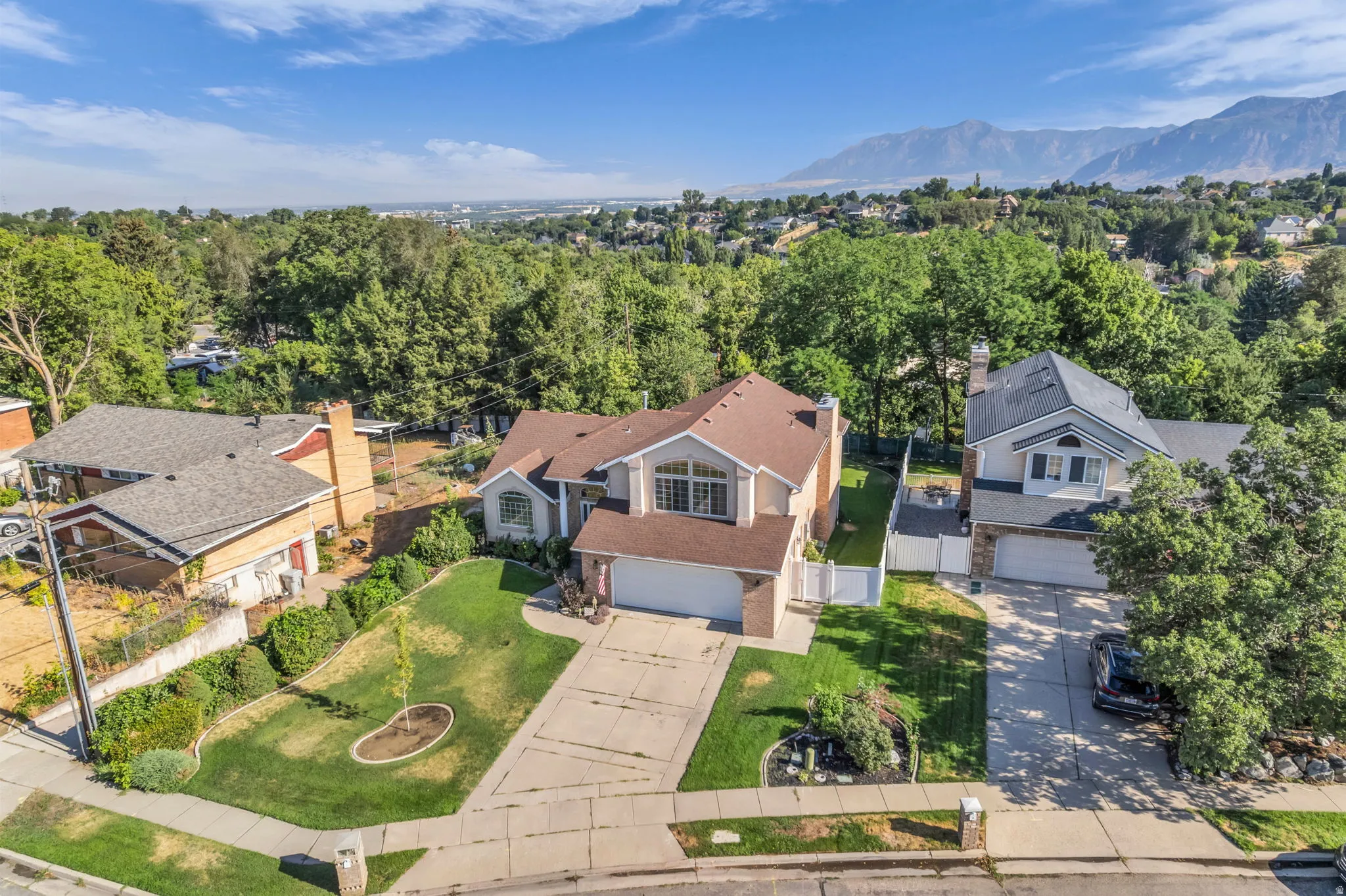 Two-story residence featuring a front-facing attached garage, a paved driveway, and a manicured front lawn with mature landscaping
