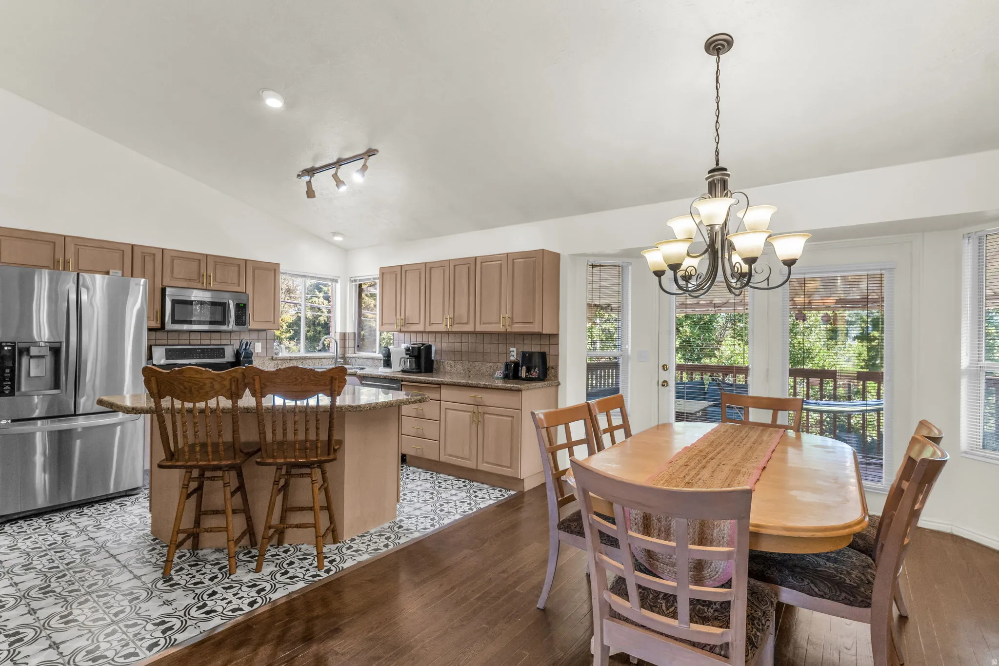 Kitchen and dining area featuring vaulted ceilings, wood-finish flooring, and a patterned tile accent