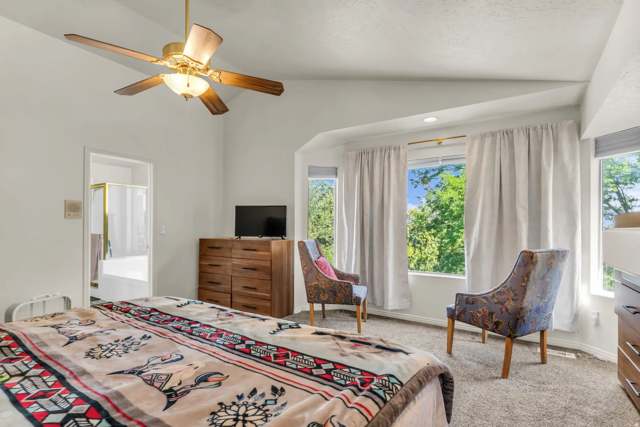 Bedroom featuring a vaulted ceiling with a ceiling fan, broad windows, and carpet flooring