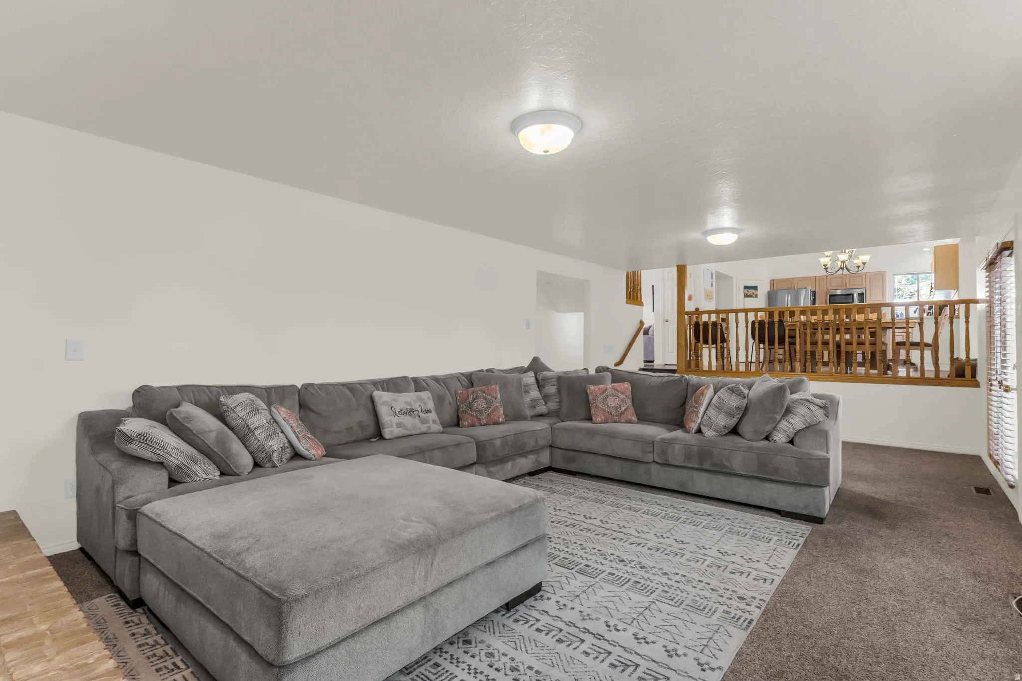 Spacious living area featuring neutral walls, recessed lighting, and mixed flooring with carpet and a decorative area rug