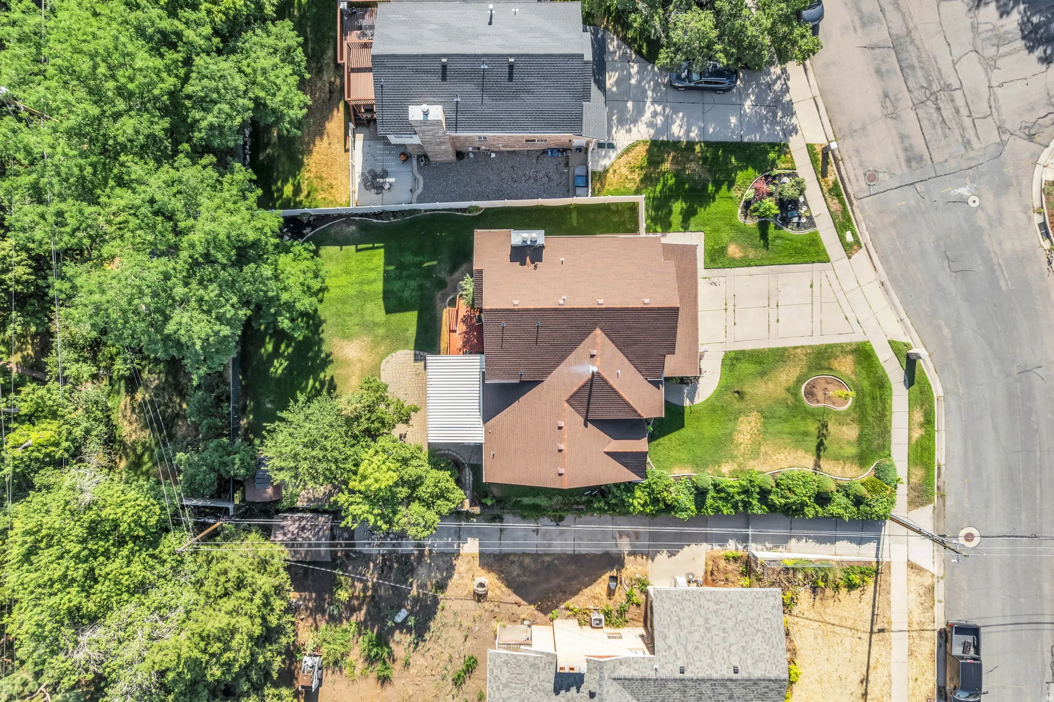 Residential property with a brown shingle roof, concrete driveway, and established front landscaping