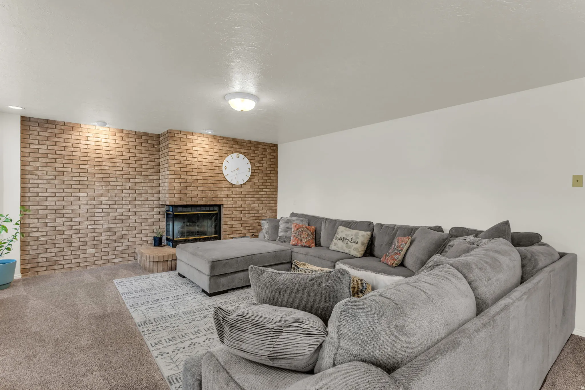 Exposed brick accent wall featuring an integrated fireplace with a black metal firebox surround