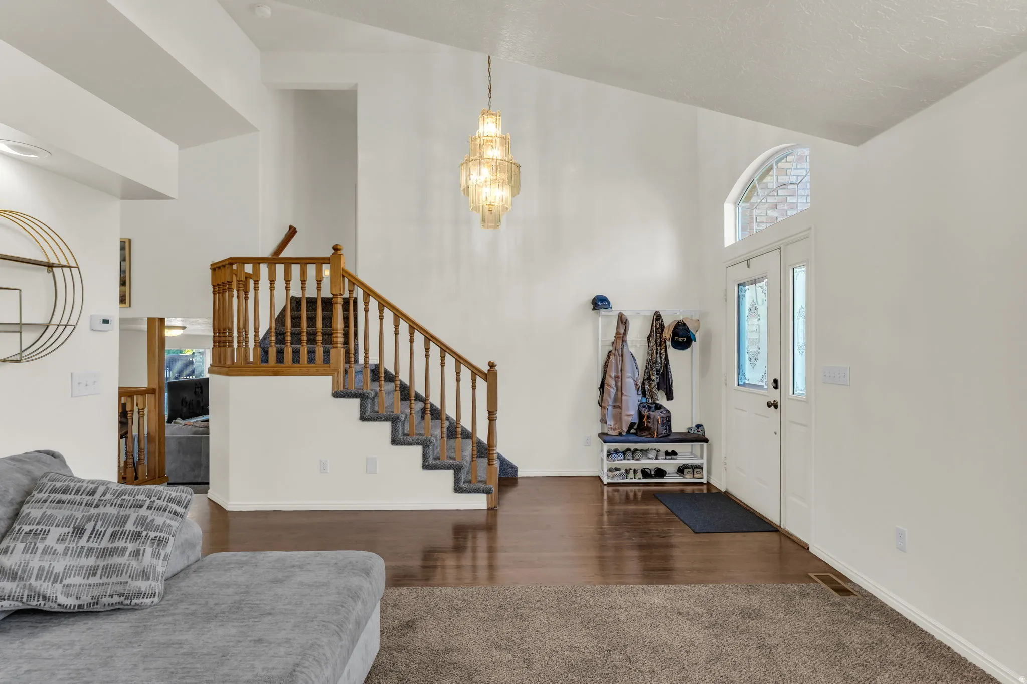 Inviting entryway with a vaulted ceiling and a tiered chandelier
