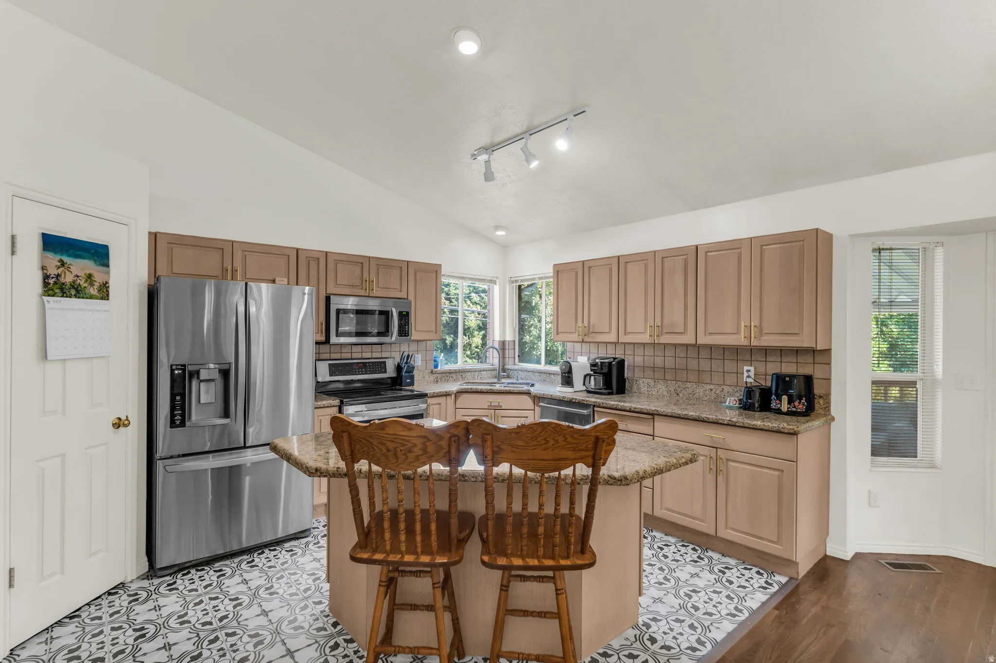 Kitchen featuring an angled ceiling, recessed lighting, and a central island with a granite countertop