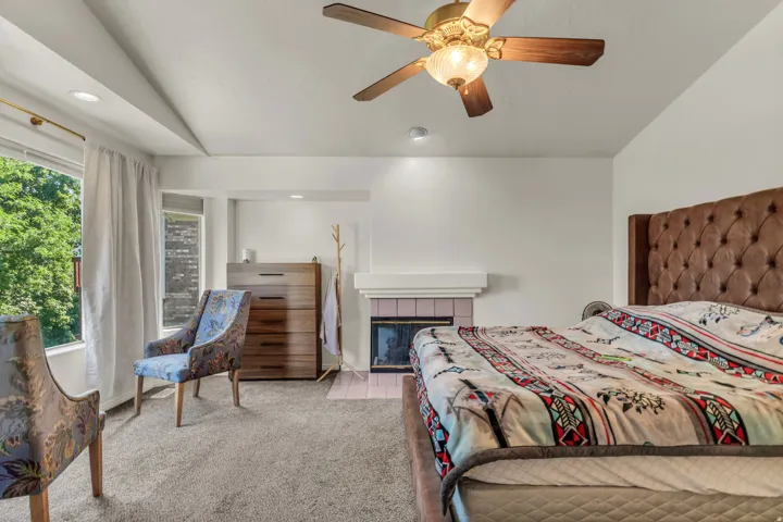 Spacious primary bedroom featuring a tufted upholstered headboard, ceiling fan with integrated lighting, recessed ceiling lights, and direct access to a private outdoor space