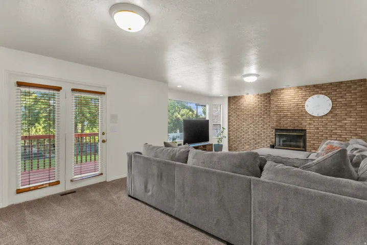 Living area featuring a brick accent wall with an integrated fireplace, plush carpet flooring, and recessed lighting