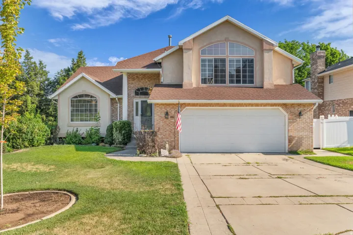 Front elevation featuring brick and stucco siding, a two-car garage, and multiple arched windows