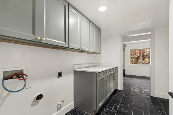 Utility room featuring gray shaker cabinetry, white countertop, and dark herringbone tile flooring