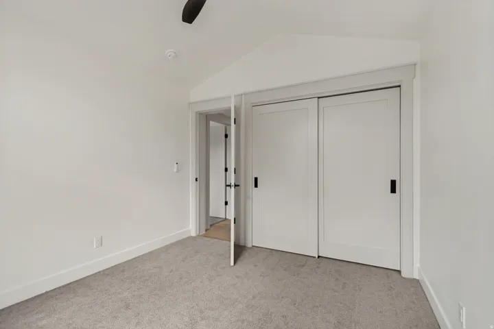 Bedroom featuring vaulted ceiling, recessed lighting, ceiling fan, grey carpet, and white sliding closet doors with black hardware