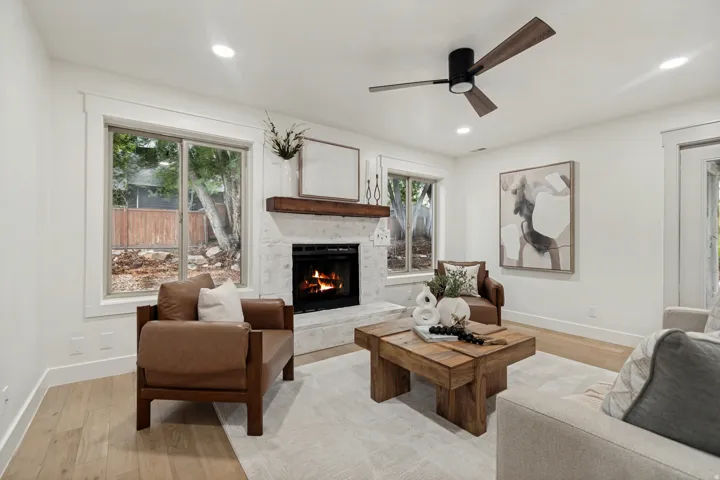 Living area featuring a stone-clad fireplace with a wood mantel, recessed lighting, and wood-finish flooring