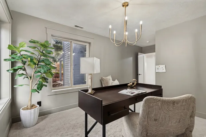 Carpeted room with neutral wall tones and a brass chandelier